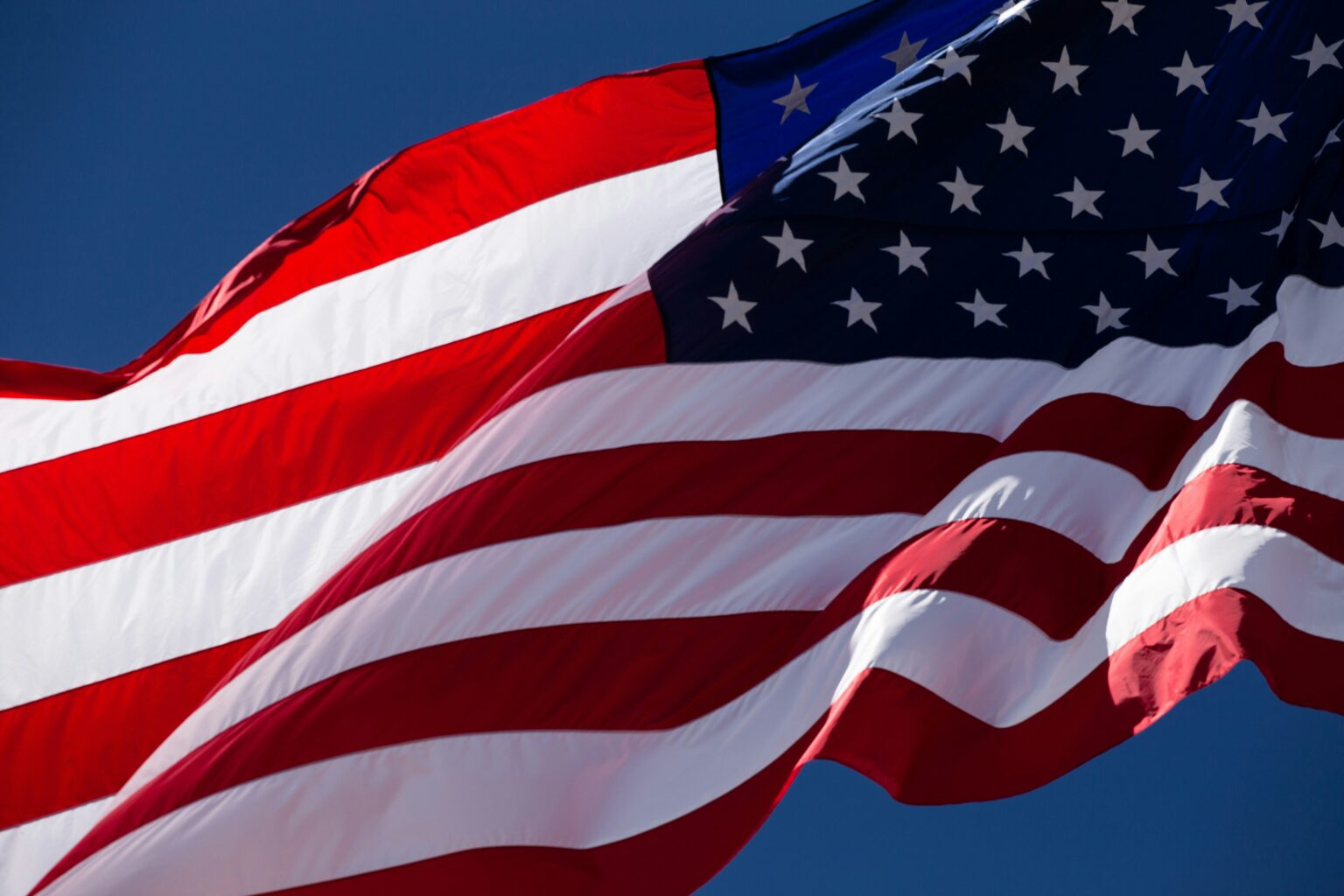 CFTC Opens Phantom-Style Compliance Path to Crypto Wallets and DeFi Interfaces Waving American flag fills the frame against a clear blue sky