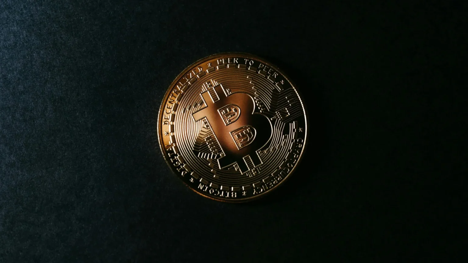 Bitcoin clears a key hurdle that has preceded major bull runs Close-up of a bronze Bitcoin cryptocurrency coin on a dark textured surface, featuring a raised diamond logo and blockchain-themed lettering